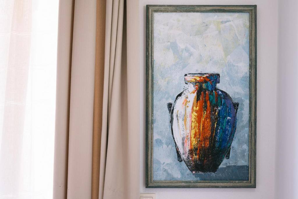 Painting of a vase on an apartment wall next to a window