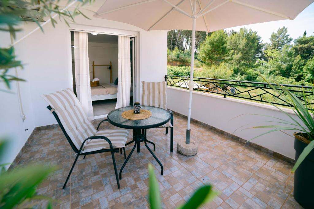 Shaded terrace with parasol, table and chairs surrounded by pine trees in Ulcinj